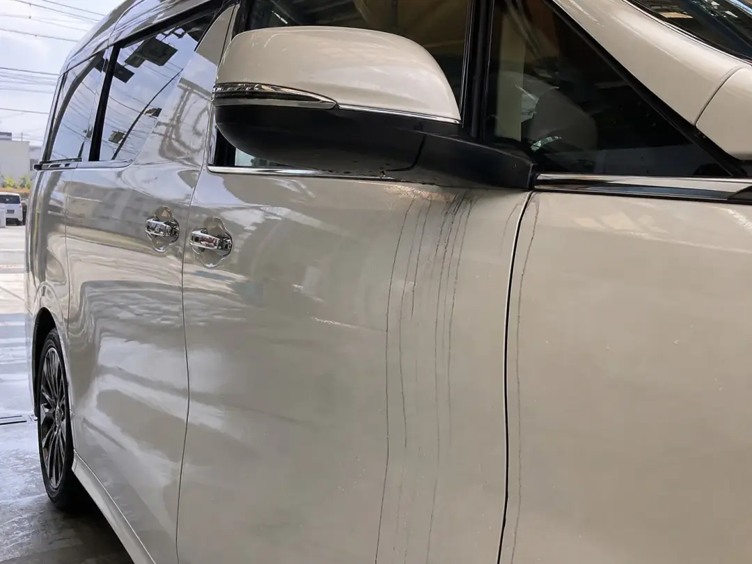 白い車のミラー下に伸びる黒い筋